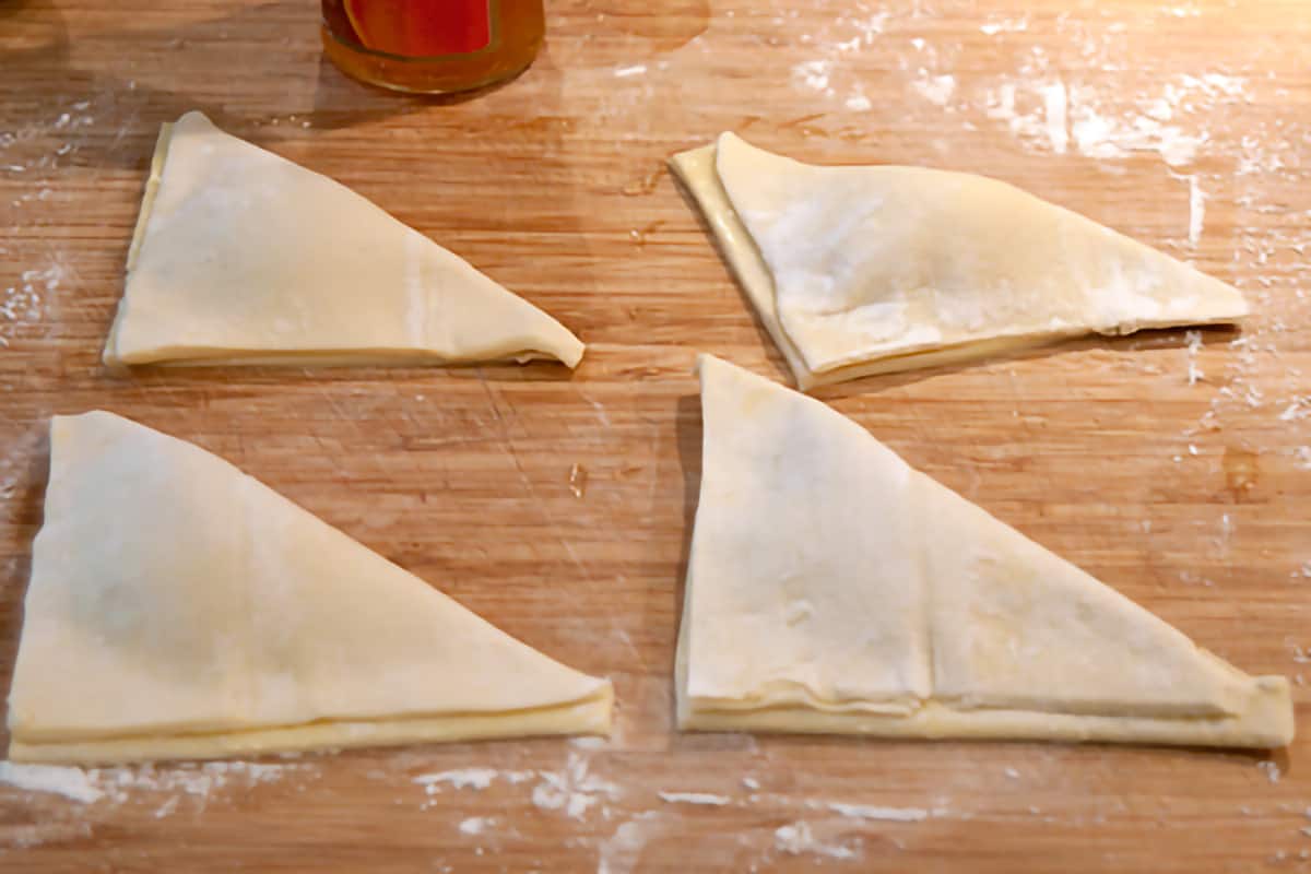 Filled puff pastry squares folded into triangles.