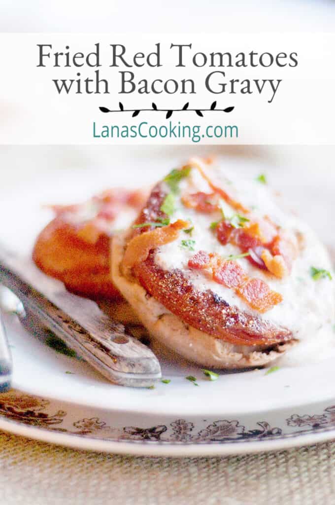 Fried red tomatoes on English muffins with gravy and crispy bacon on top.