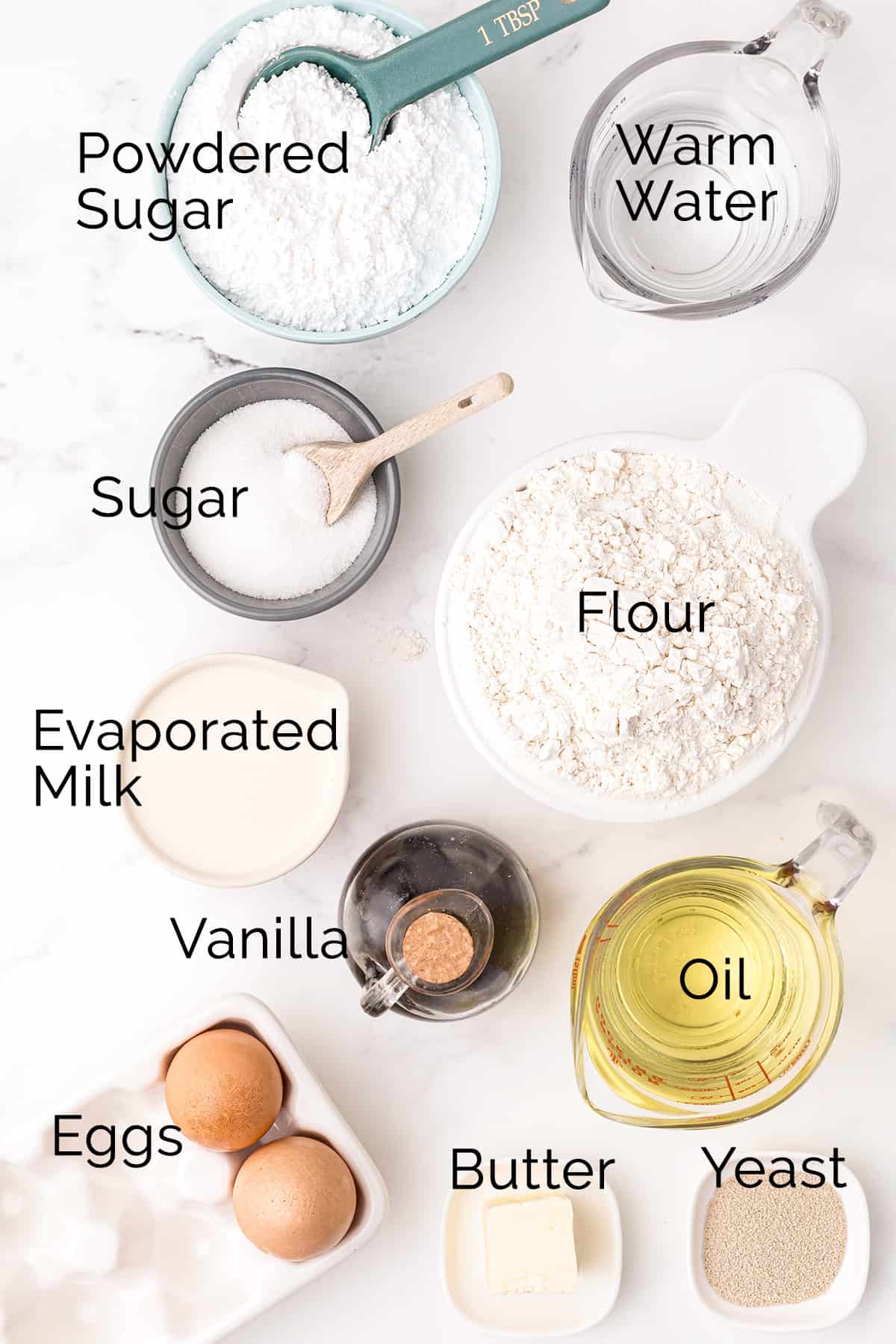 Ingredients needed to make New Orleans Beignets: powdered sugar, water, granulated sugar, flour, evaporated milk, vanilla, oil, eggs, butter, yeast.