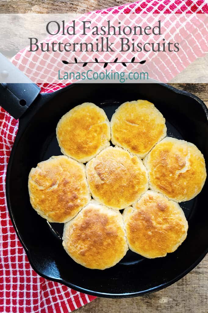 Baked buttermilk biscuits in a cast iron skillet on a wooden board.