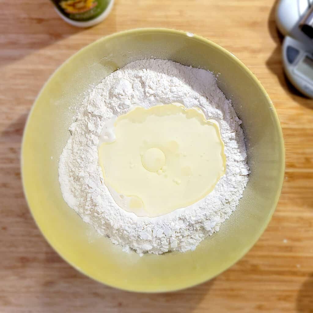 Mixing bowl containing flour, buttermilk, oil, and salt.