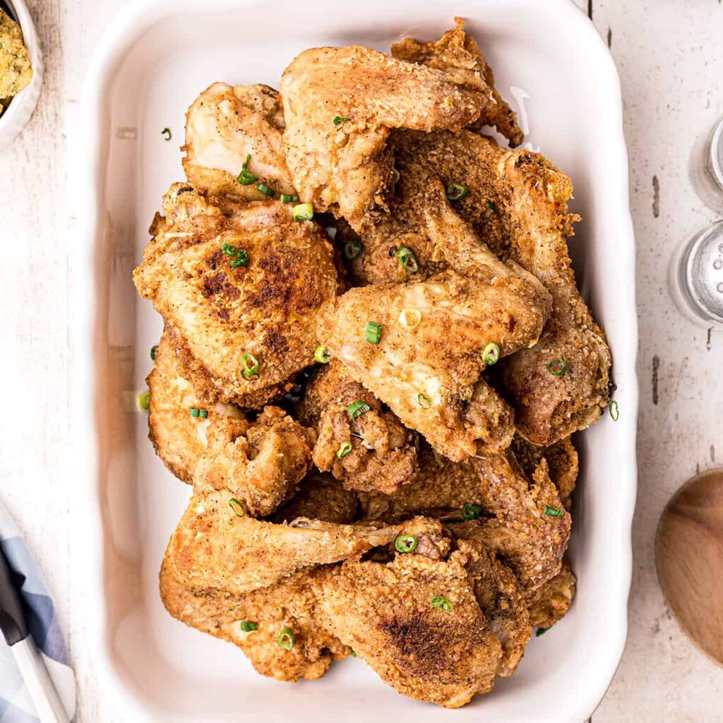 Finished fried chicken on a white serving platter.