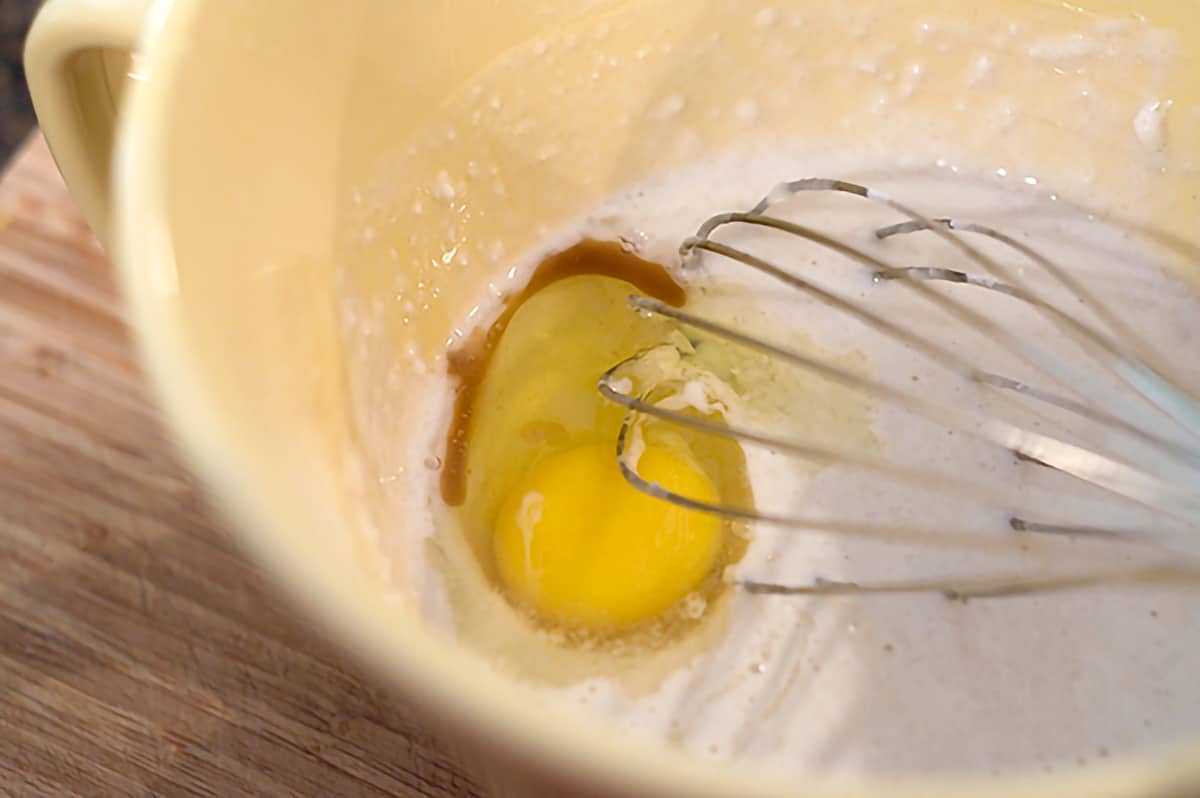 Whisking an egg and the vanilla into the muffin mixture.
