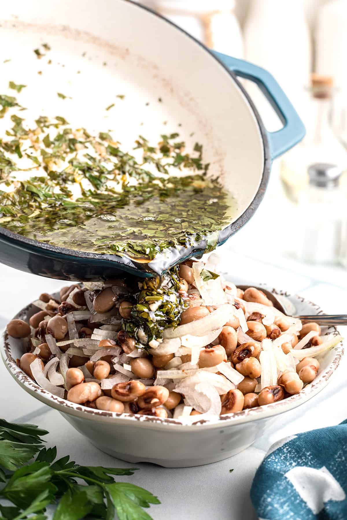 Pouring warm marinade over peas and onions.