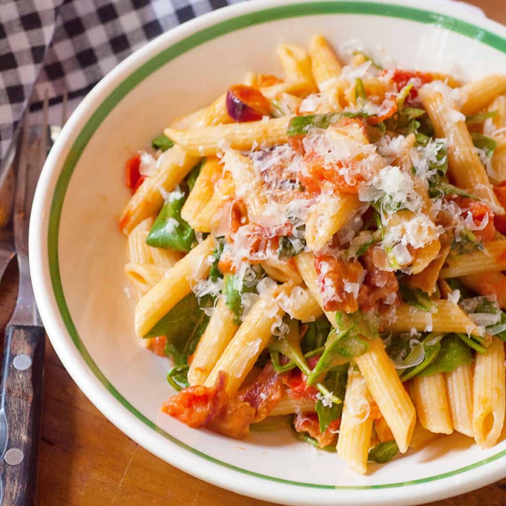 BLT pasta in a serving bowl with a napkin and cutlery alongside.