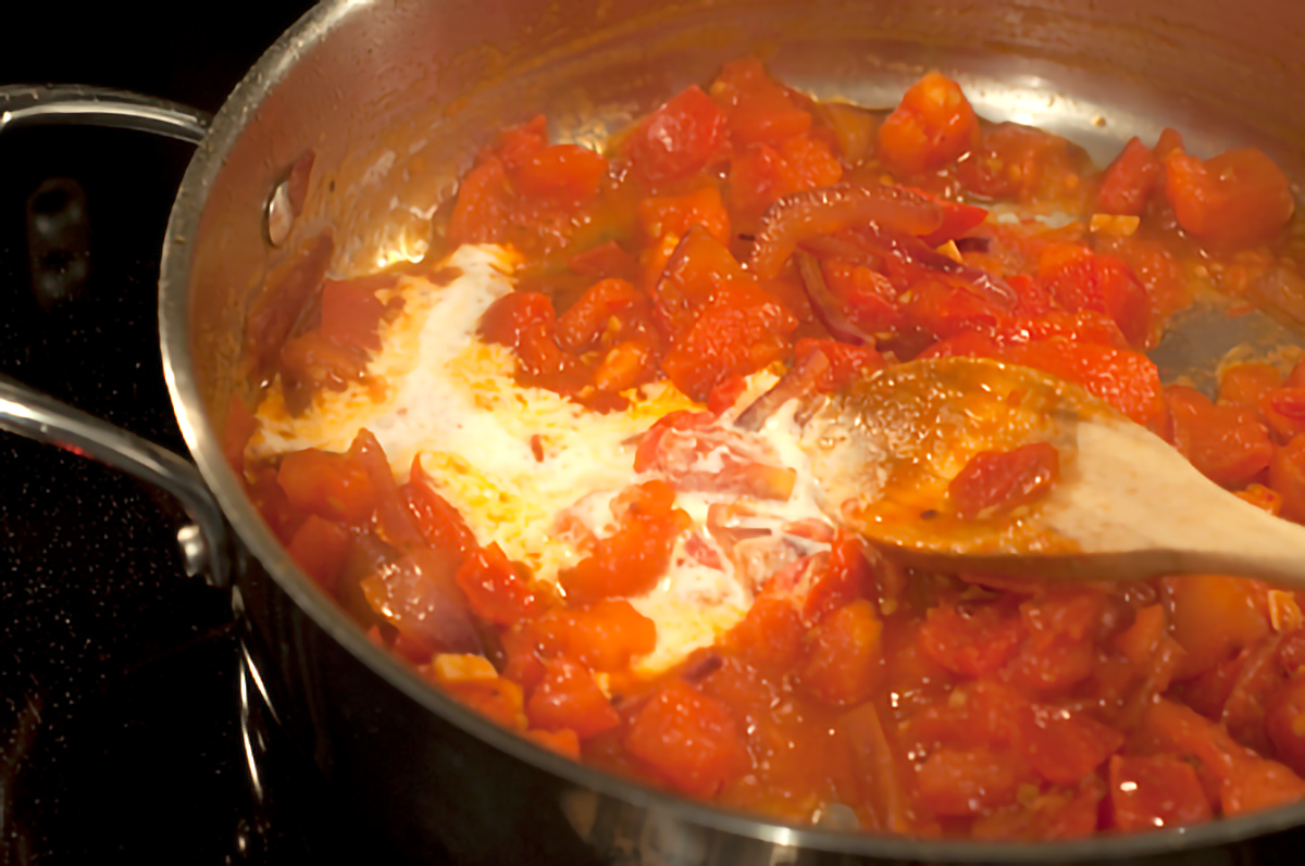 Tomatoes and cream added to skillet with cooked onions.