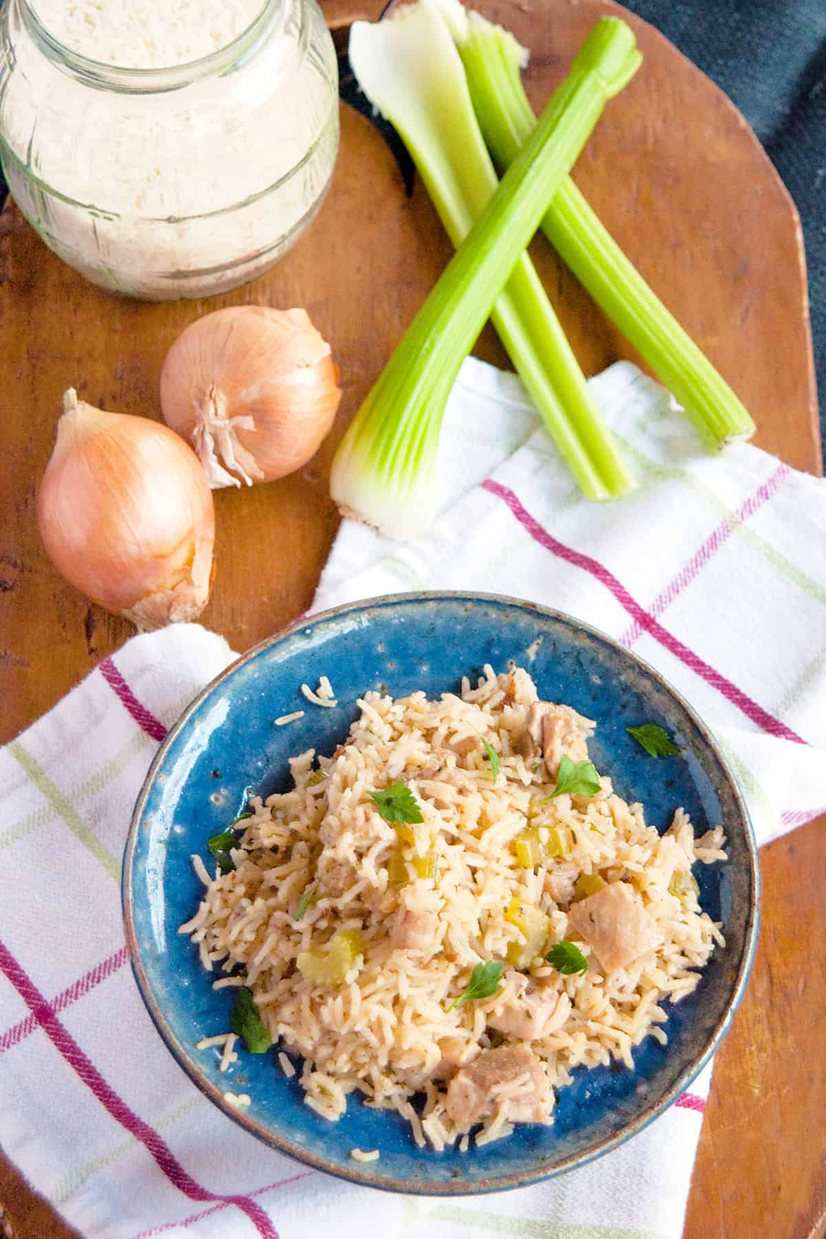 Chicken and rice in a blue bowl on a wooden board.