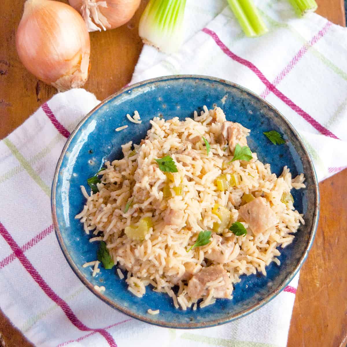 Chicken and rice in a blue bowl on a wooden board.