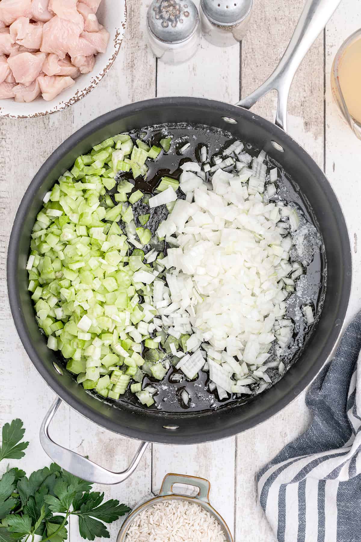 Onions and celery added to melted butter in a skillet.