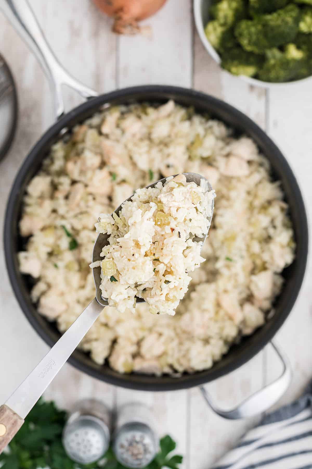 A spoonful of chicken and rice held above a pan.