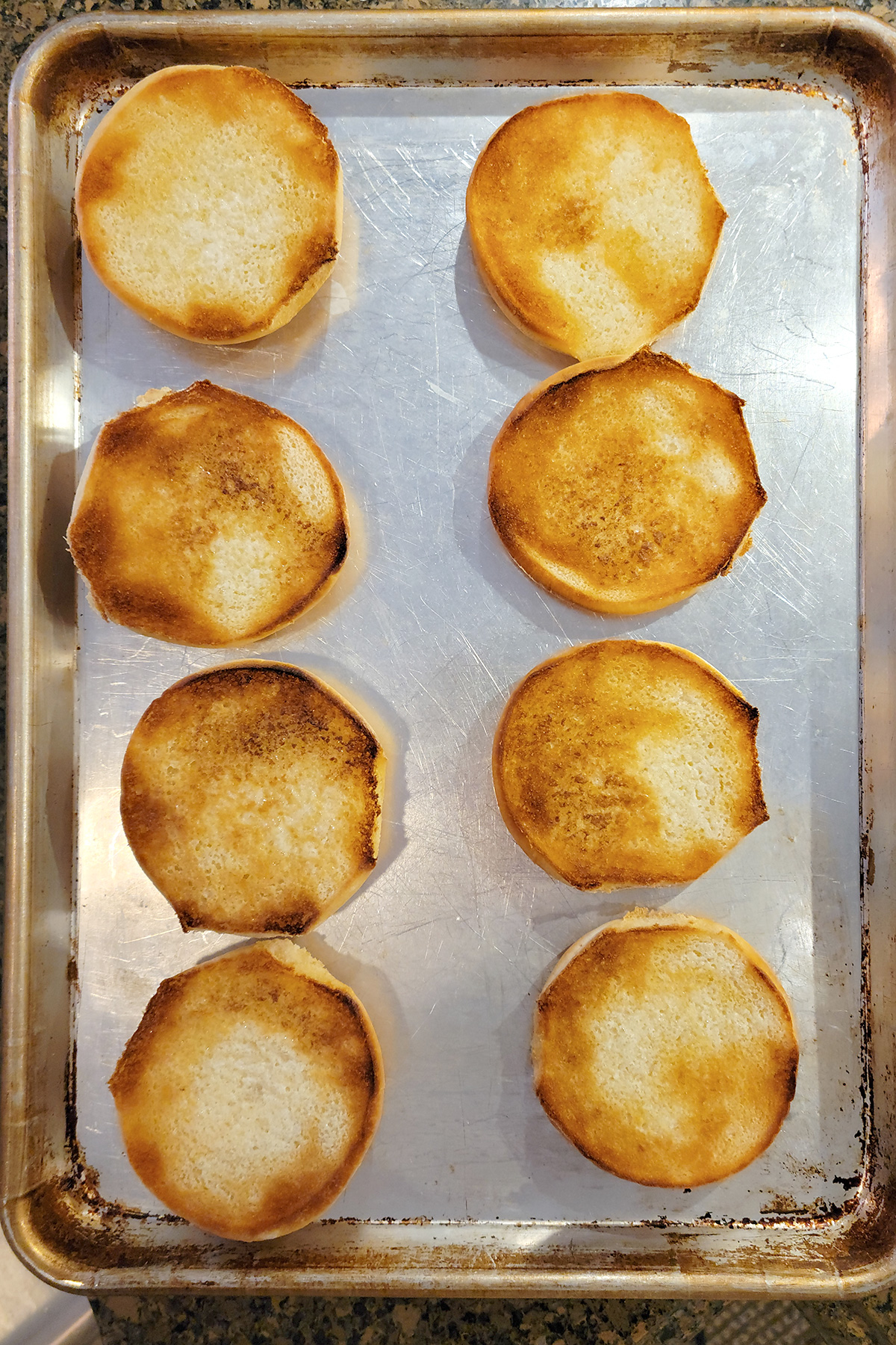 Hamburger buns on a baking sheet after toasting.