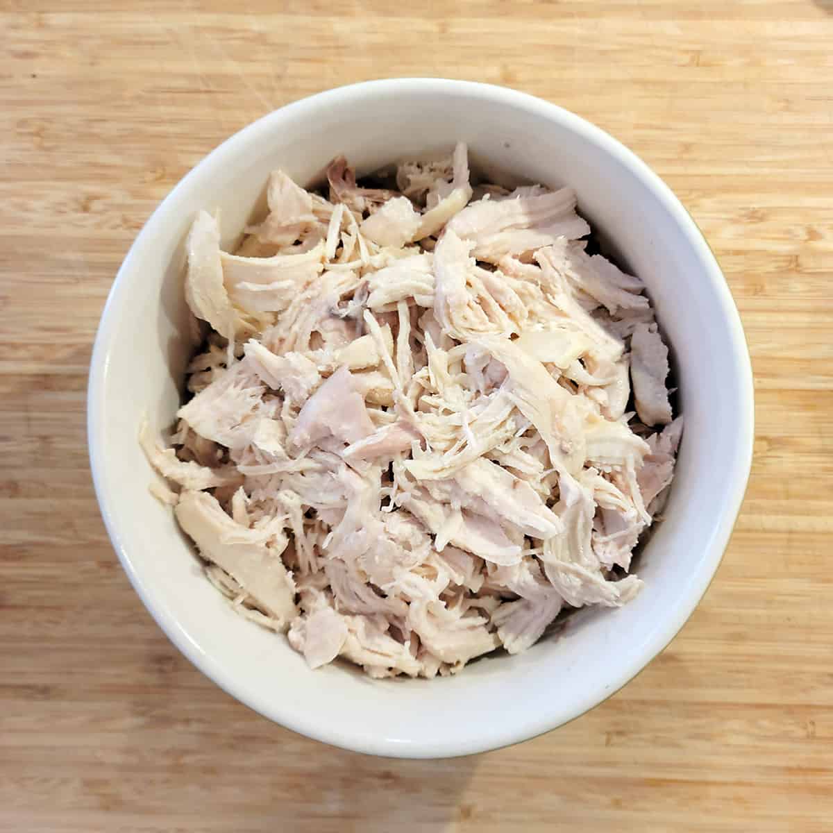 Chicken with skin and bones removed in a mixing bowl.