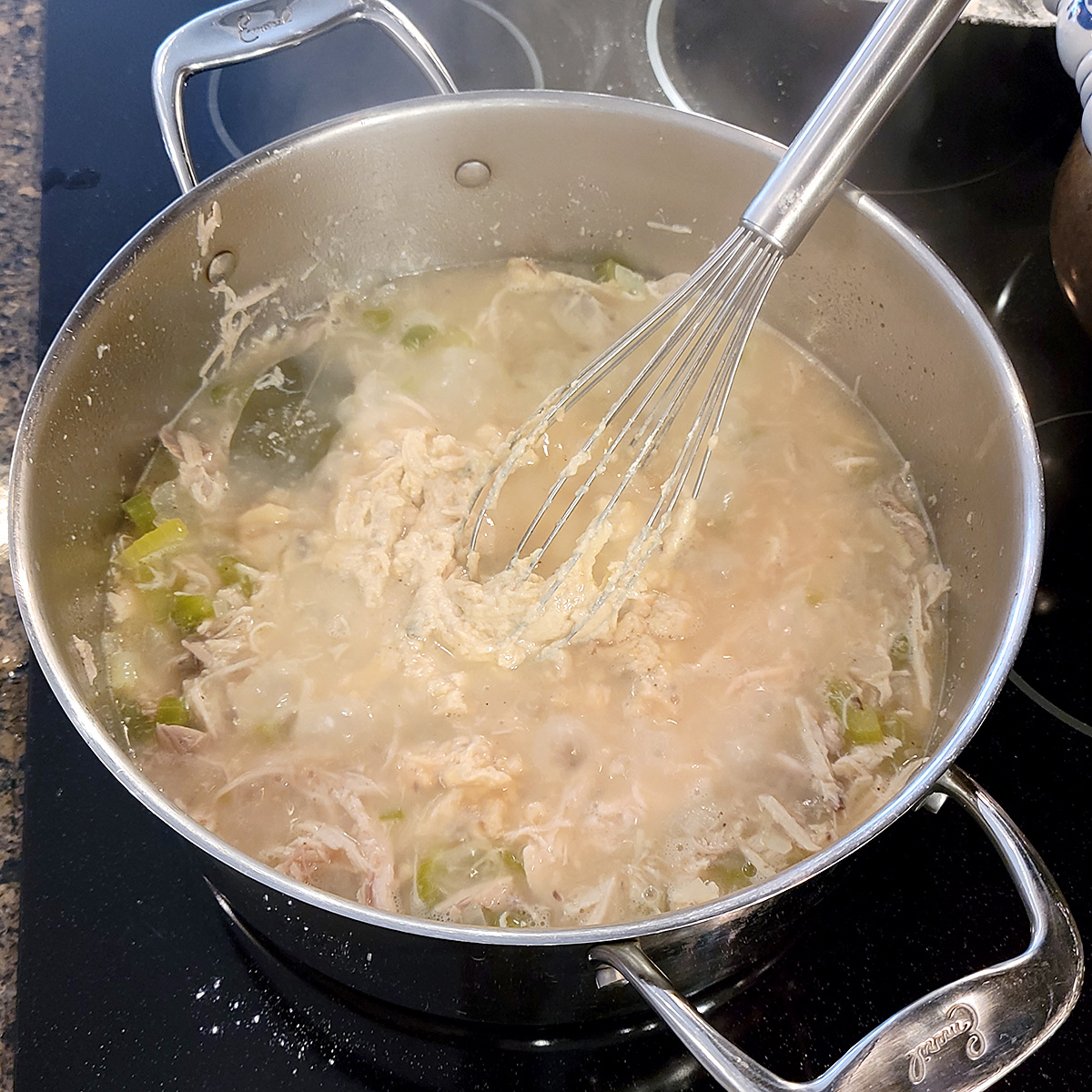 Soup, butter, flour mixture being whisked into boiling stock and meat.