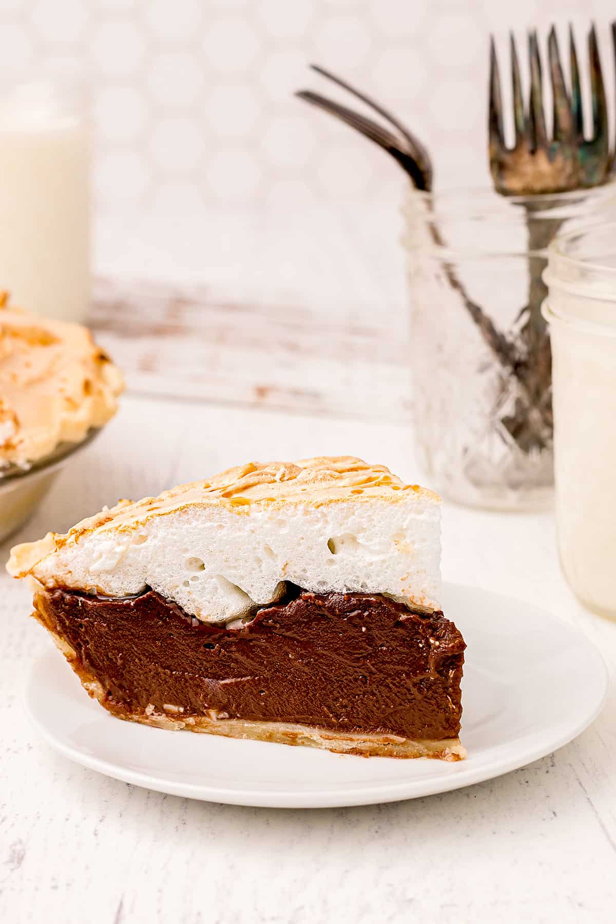 A slice of old fashioned chocolate meringue pie on a white serving plate.