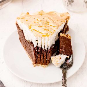 A slice of old fashioned chocolate meringue pie on a white serving plate.