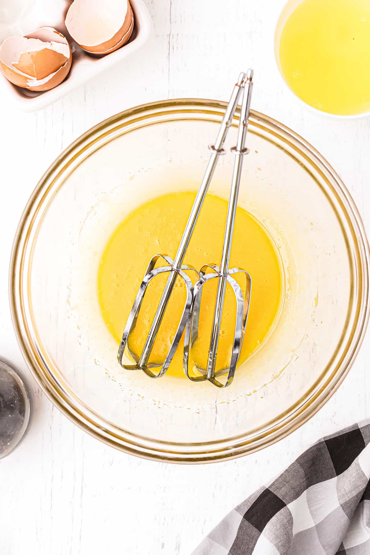 A mixing bowl holding egg yolks and mixer beaters.