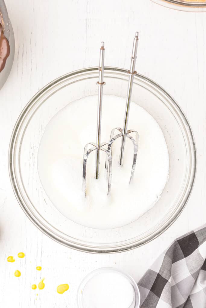 Beaten egg whites and beaters in a mixing bowl.