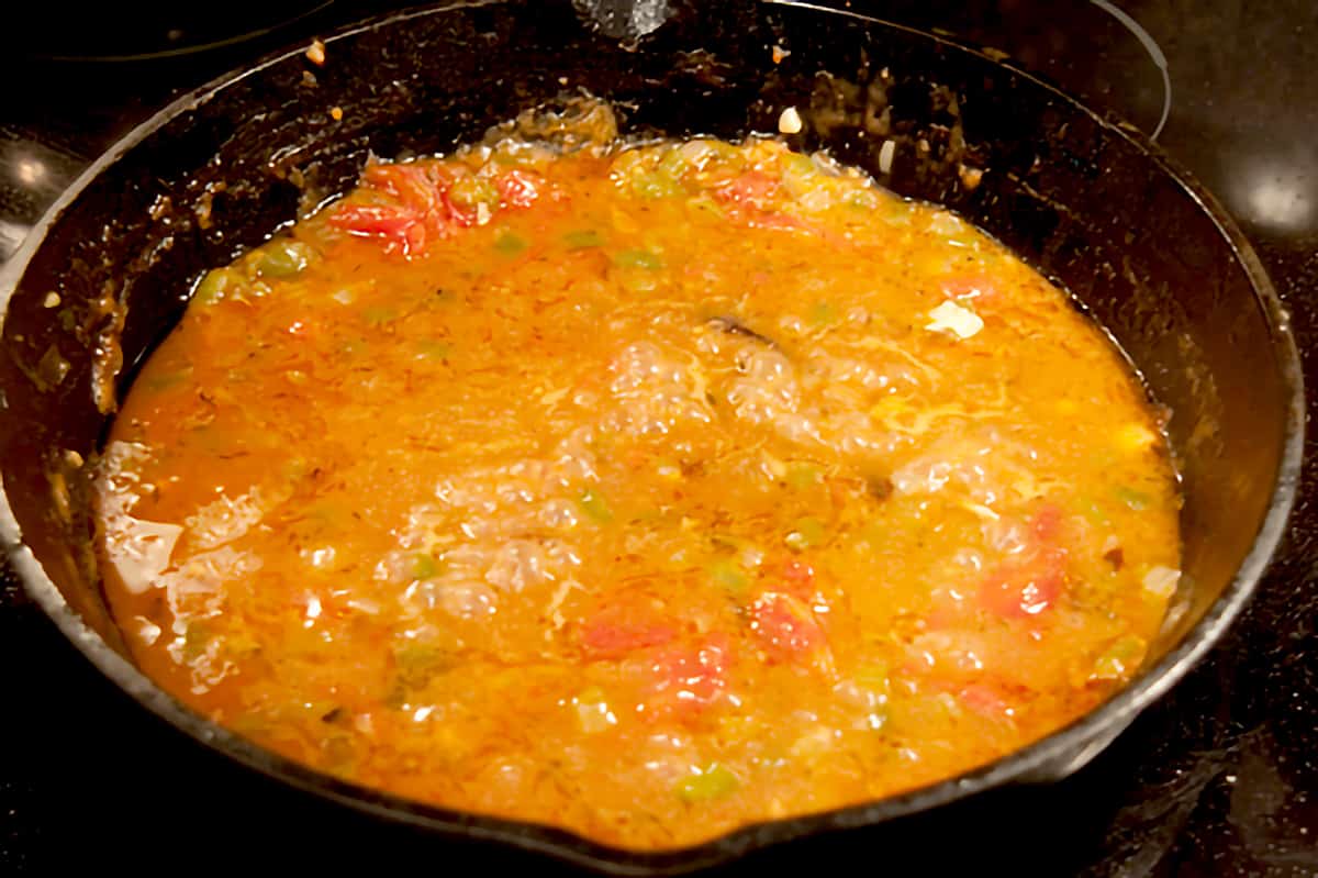 Creole sauce reducing in cast iron skillet.