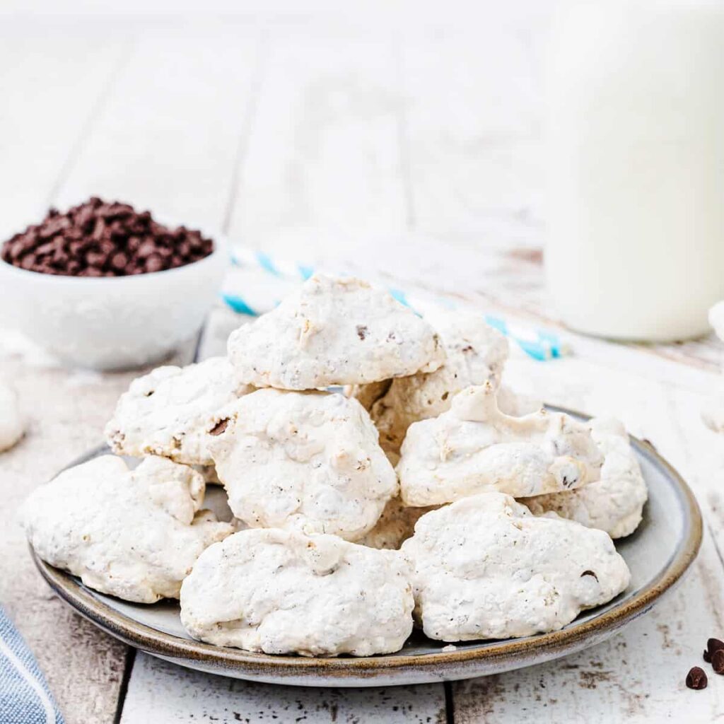 Forgotten cookies on a serving plate with milk and chocolate chips in the background.