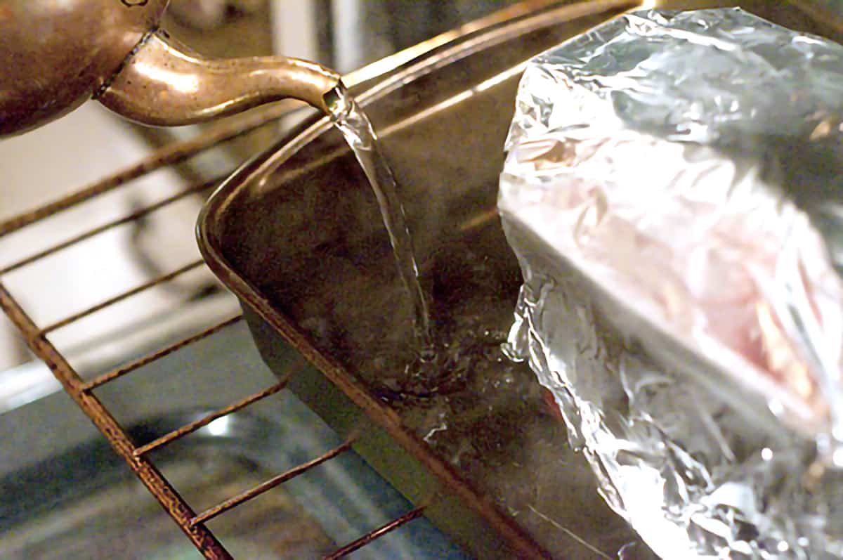 Pouring boiling water into a baking pan holding the prepared terrine.