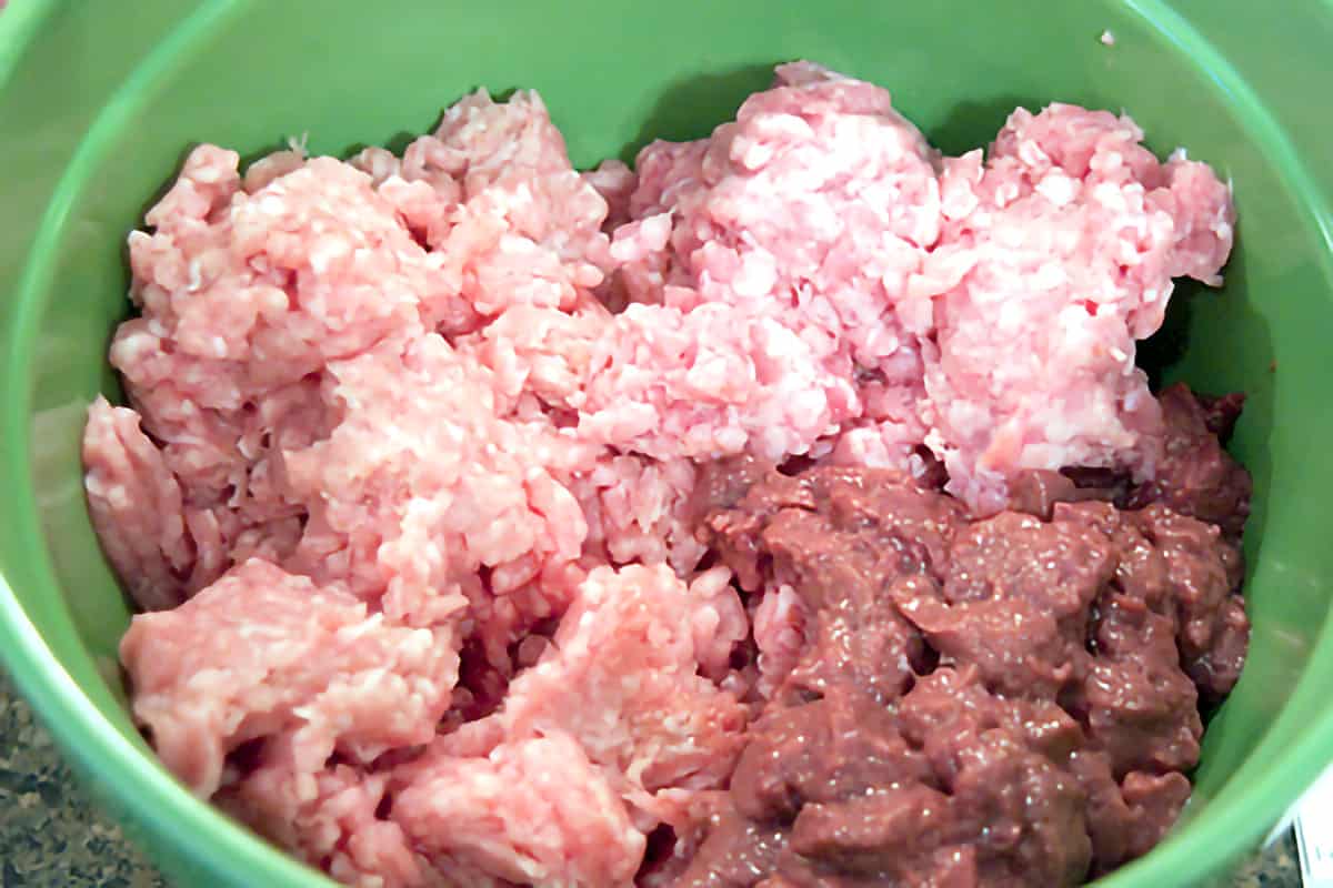 Meats for the terrine in a green mixing bowl.