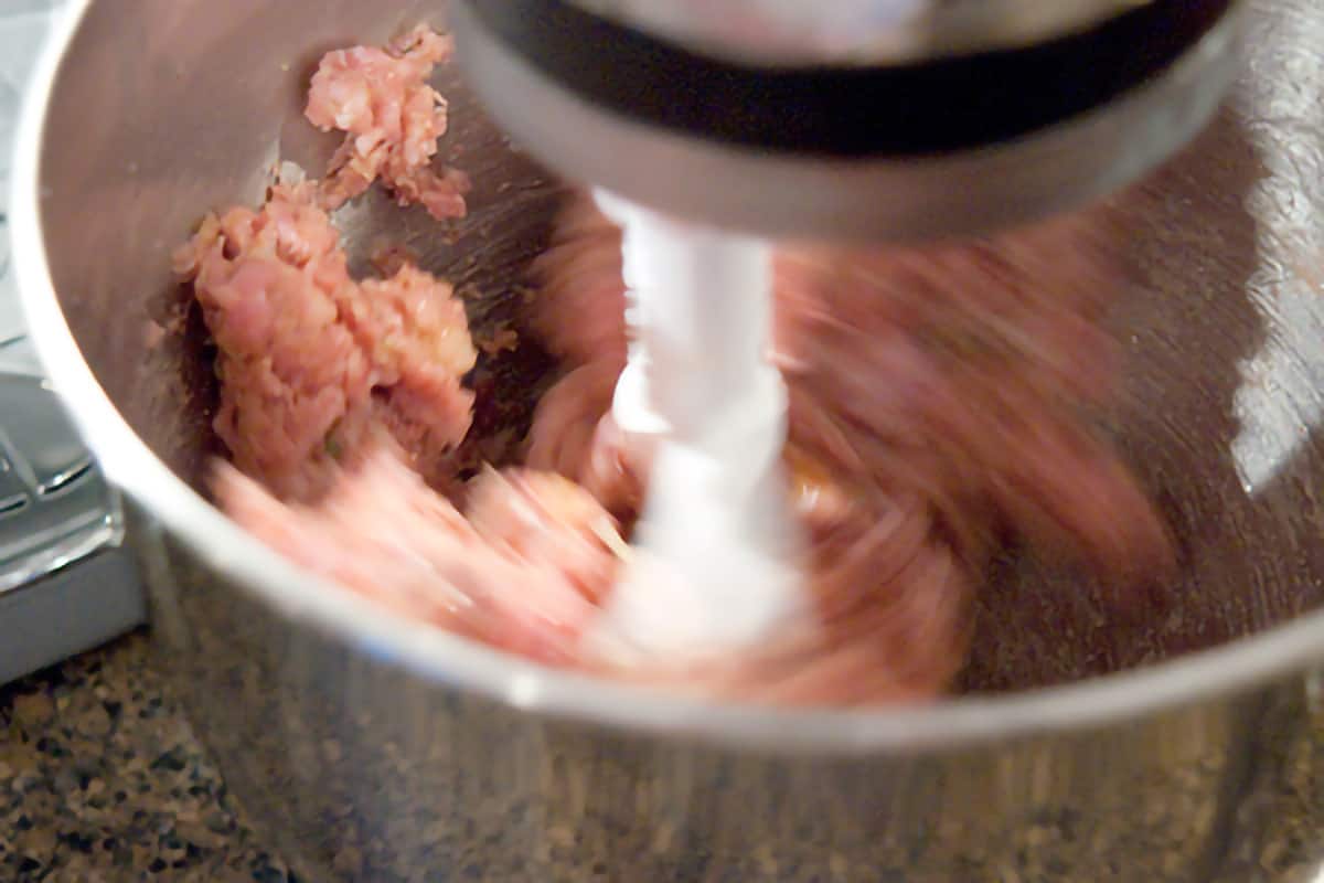 Combining the meats in the bowl of a stand mixer.