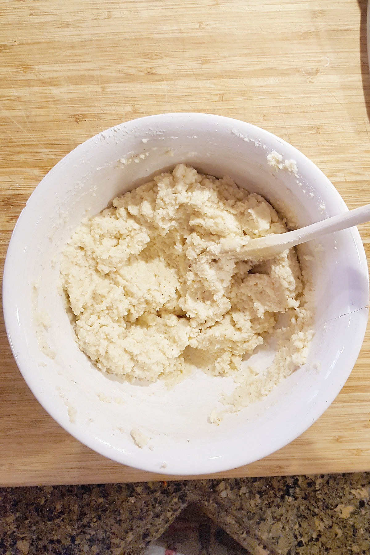 Cornmeal batter and a wooden spoon in a mixing bowl.