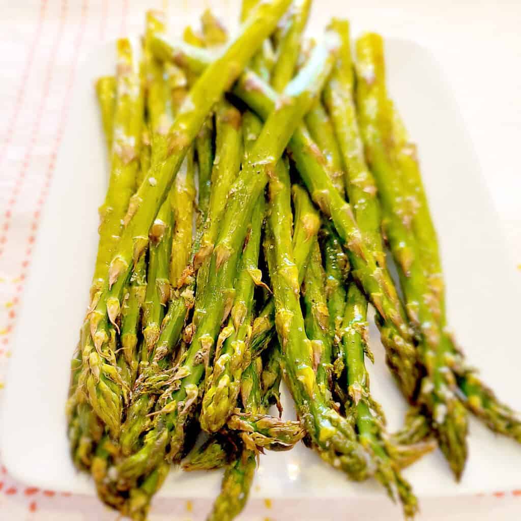 Oven roasted asparagus on a white serving dish.