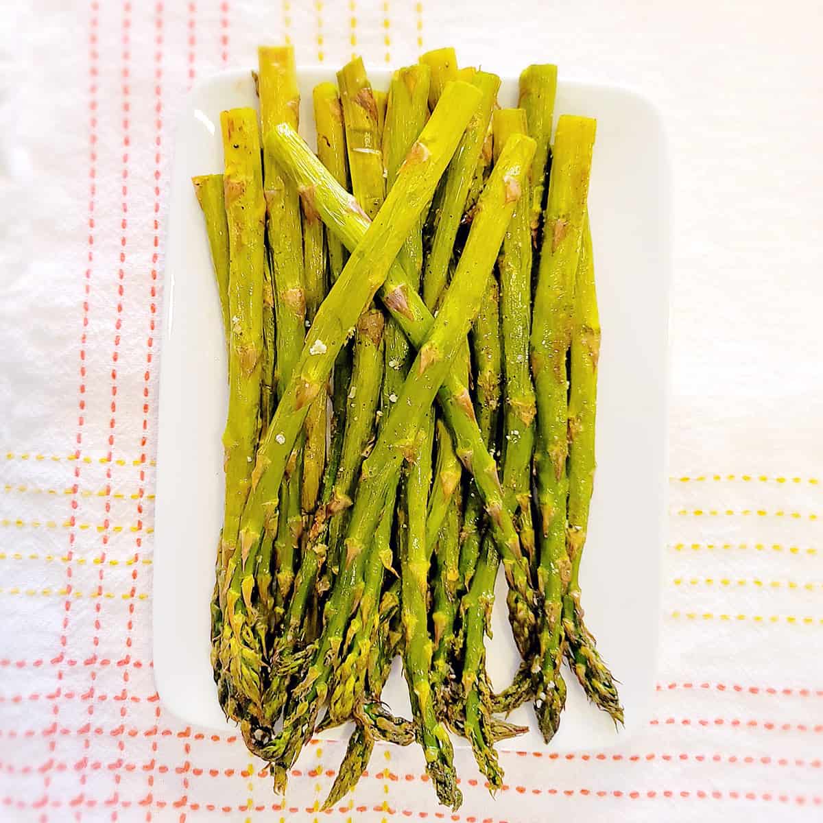 Oven roasted asparagus on a white serving dish.