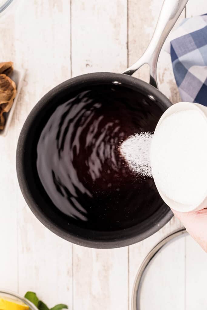 Pouring sugar into pot with warm steeped tea.