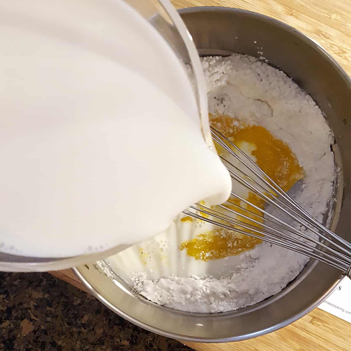 Mixing sugar, flour, and salt with eggs and milk in top of double boiler.