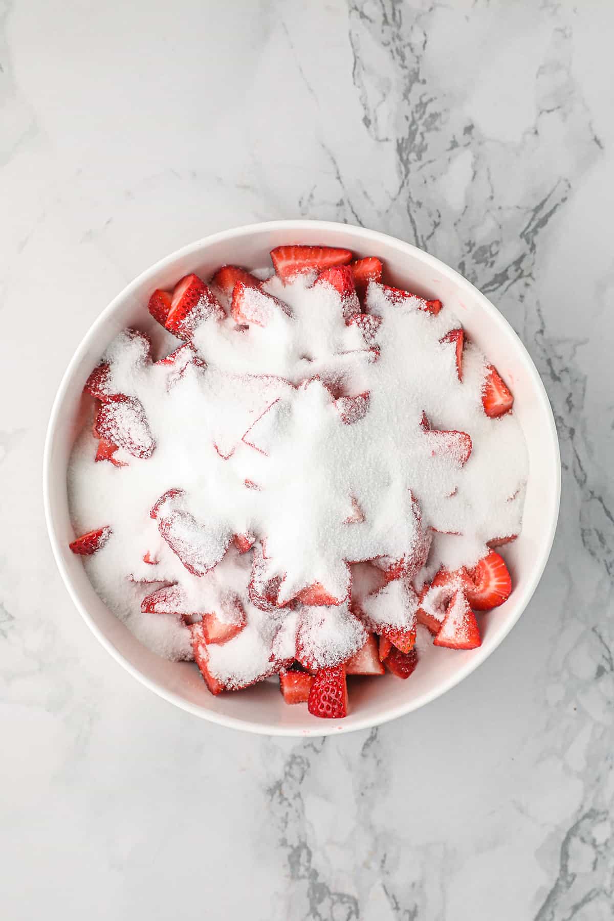 Strawberries and sugar in a bowl.