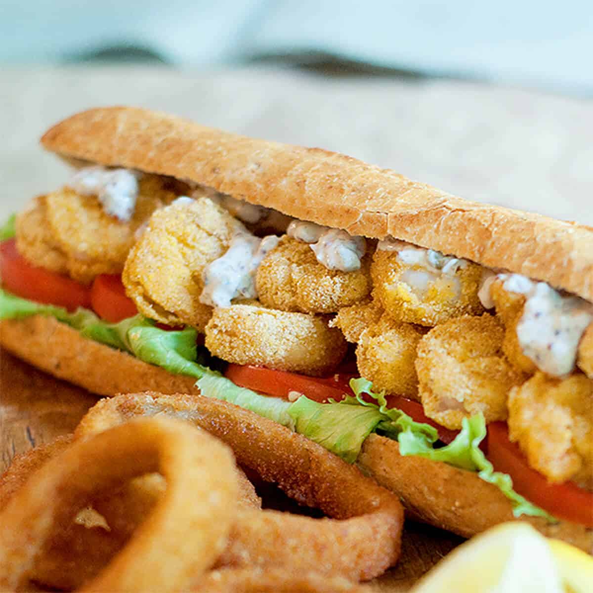 Shrimp Po' Boy with onion rings in the foreground.