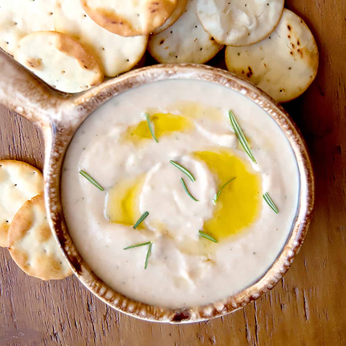 Spicy white bean dip in a small brown bowl.
