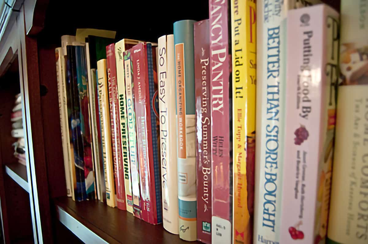 A row of canning reference books in a bookcase.