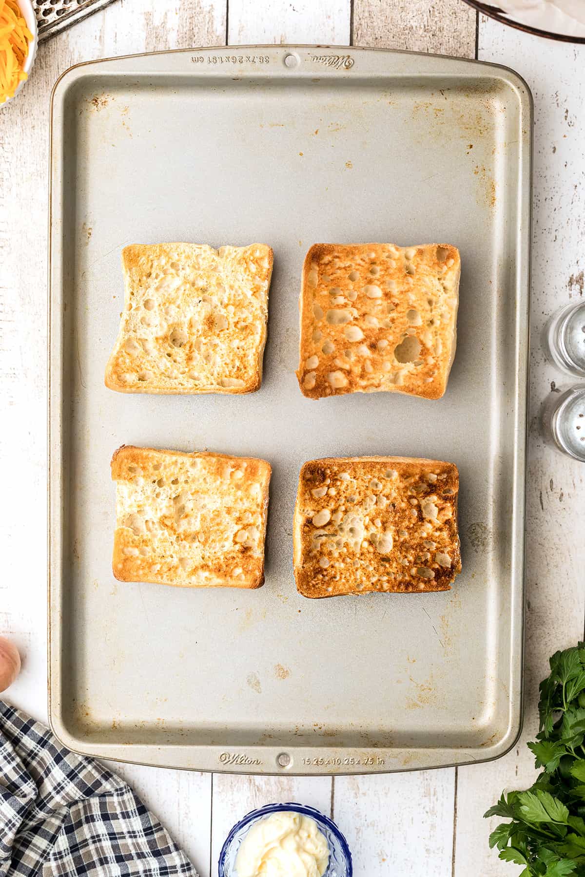 Toasted ciabatta rolls on a baking sheet.