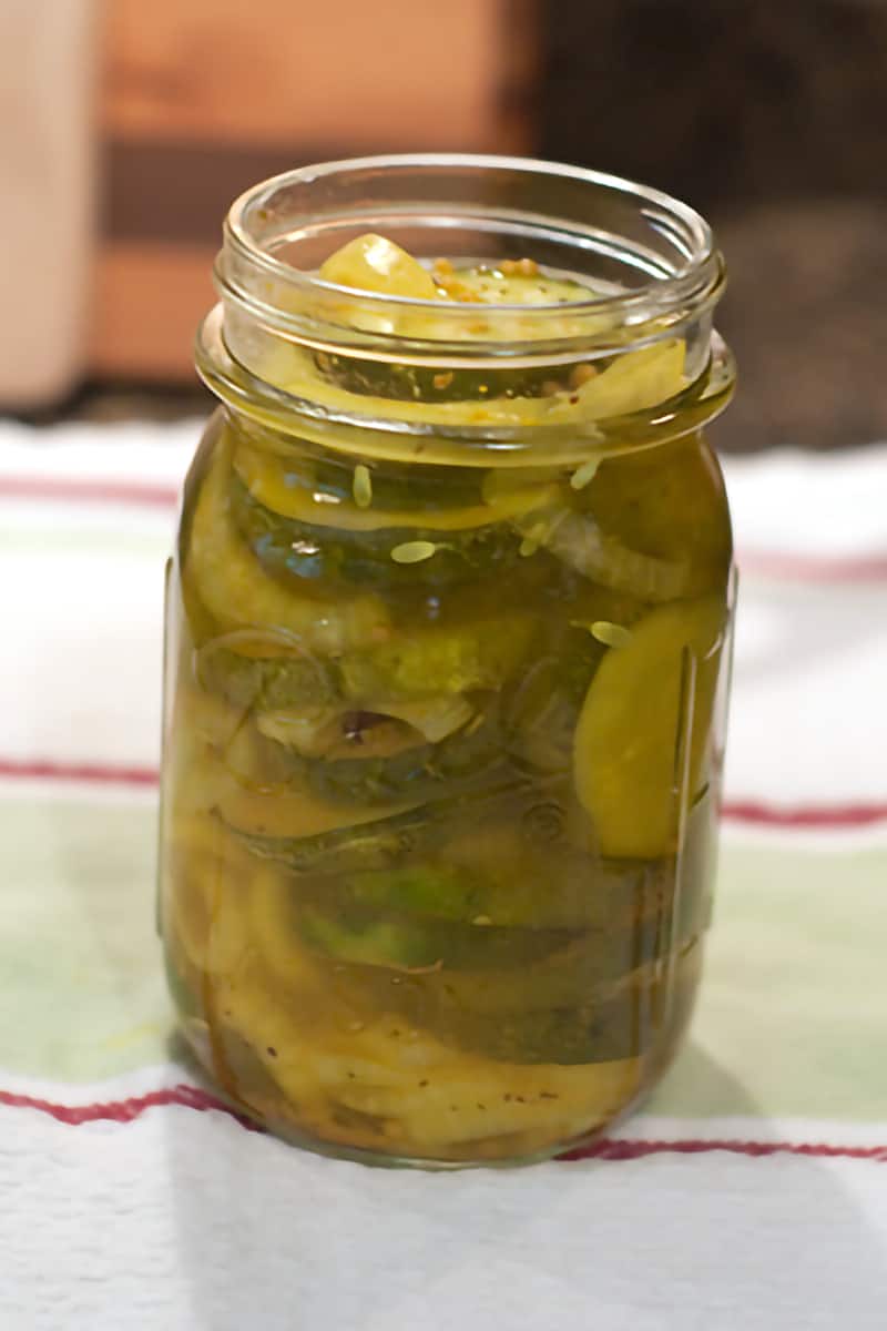 Canning jar filled with cucumbers, onions, and pickling liquid.