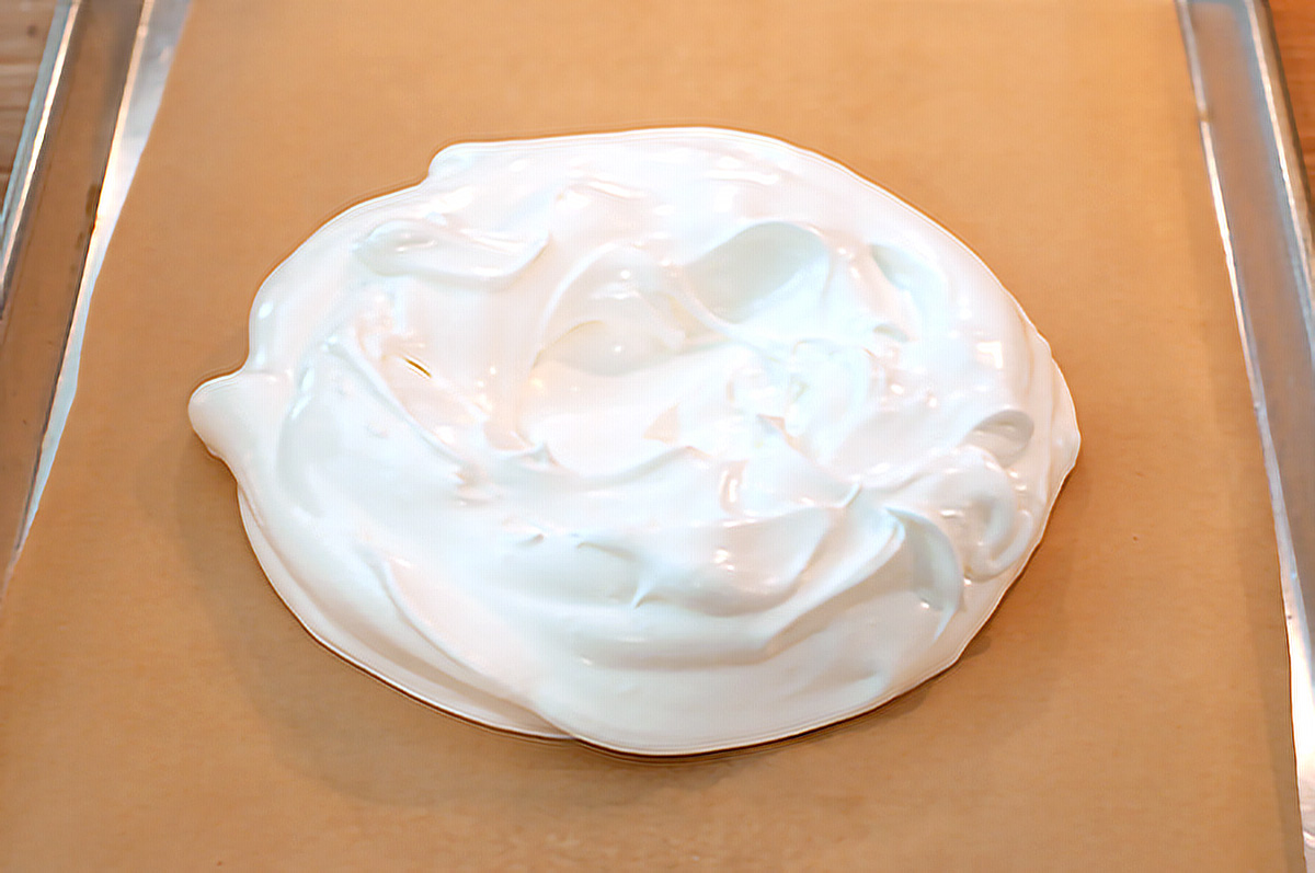 Meringue formed into a circle on parchment paper lined baking sheet.