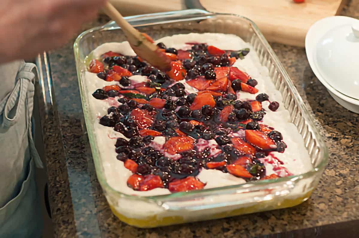 Adding fruit and basil to top of batter mixture.