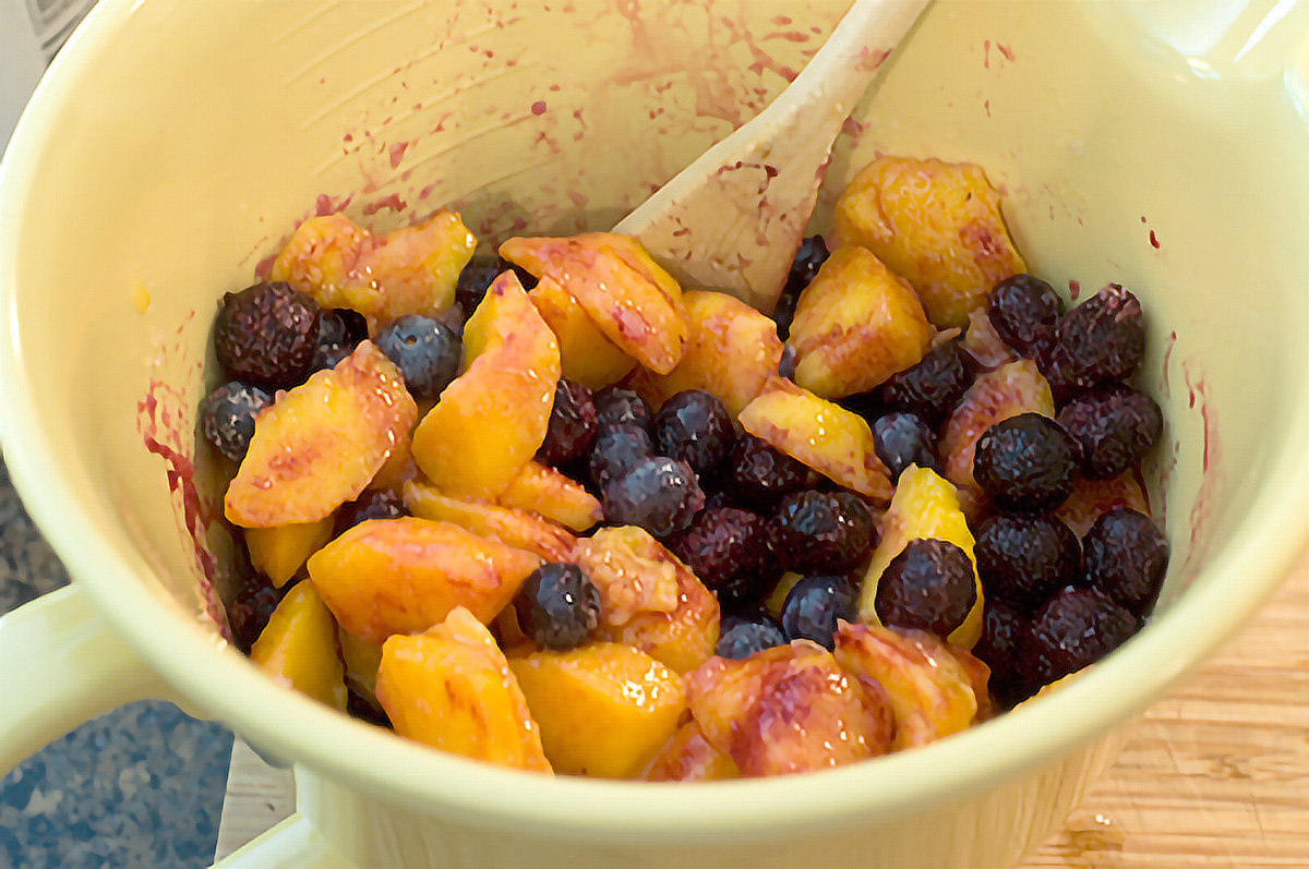 Peaches and blueberries in a mixing bowl.