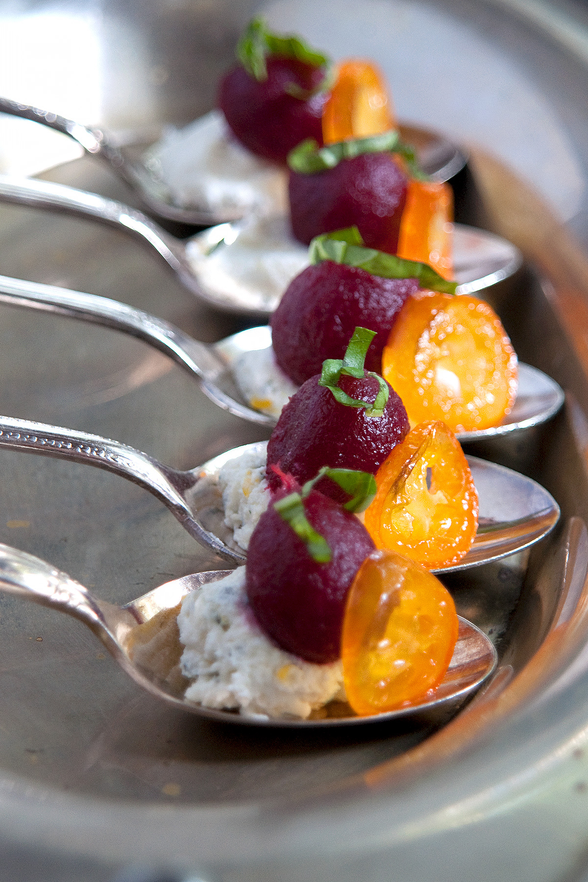 Pickled baby beets with herbed goat cheese amuse buche in individual silver spoons.
