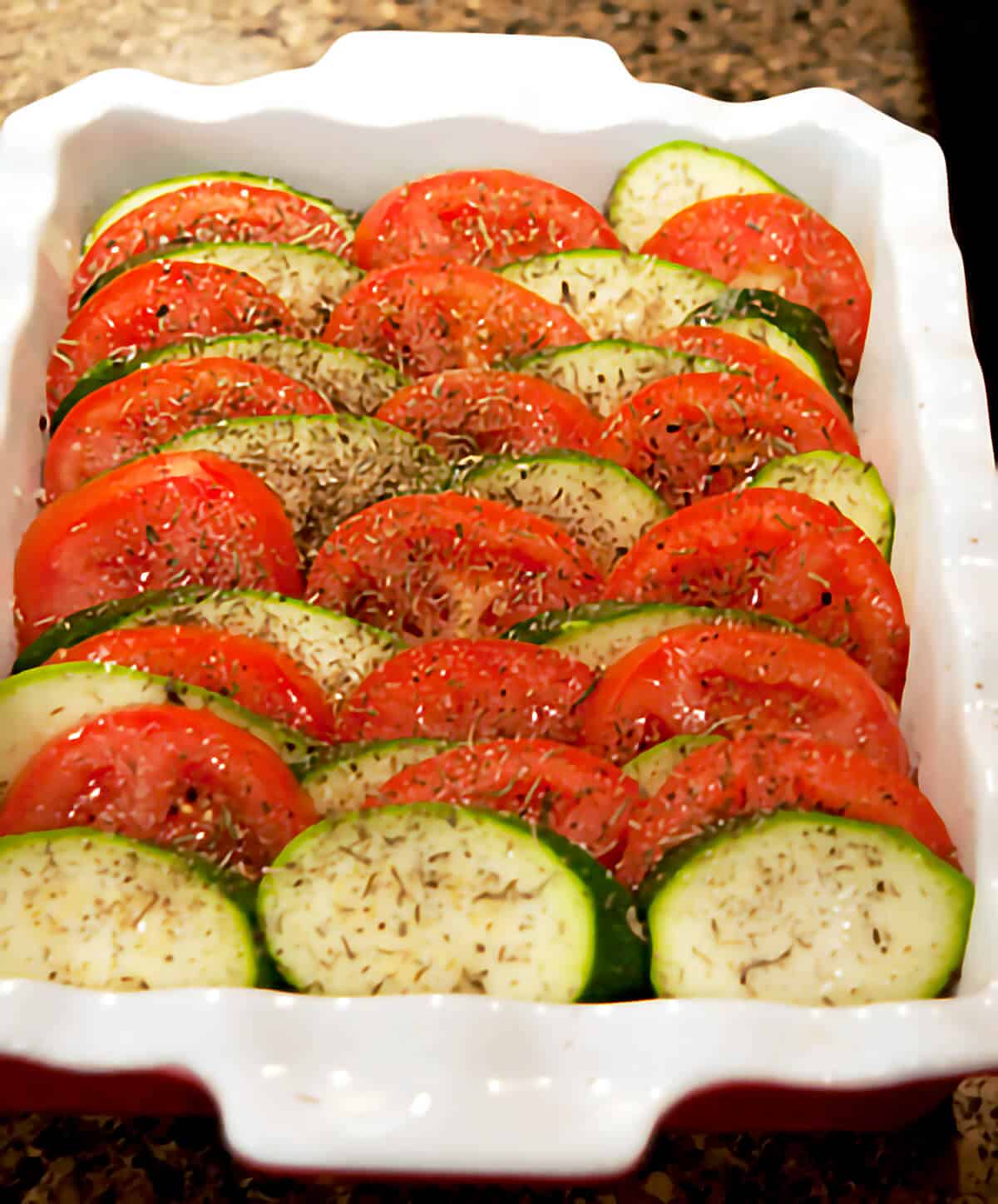 Zucchini and tomato slices layered in a baking dish.