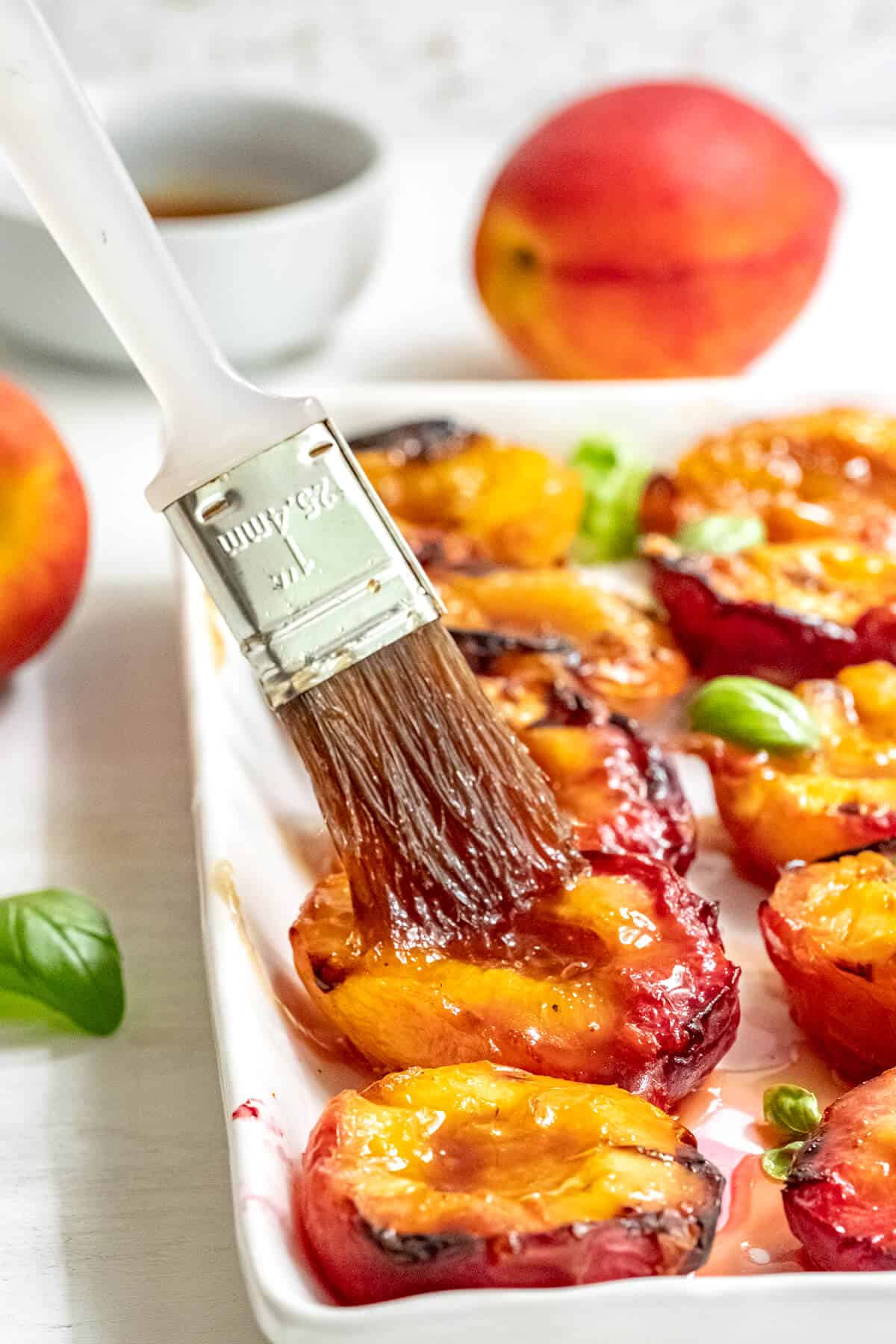 Brushing grilled peaches with glaze.