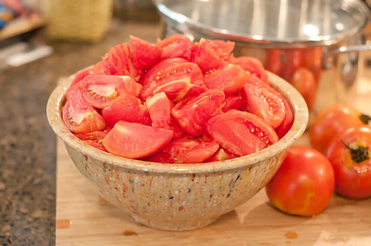 Large bowl heaped full of tomatoes prepared and ready for canning.