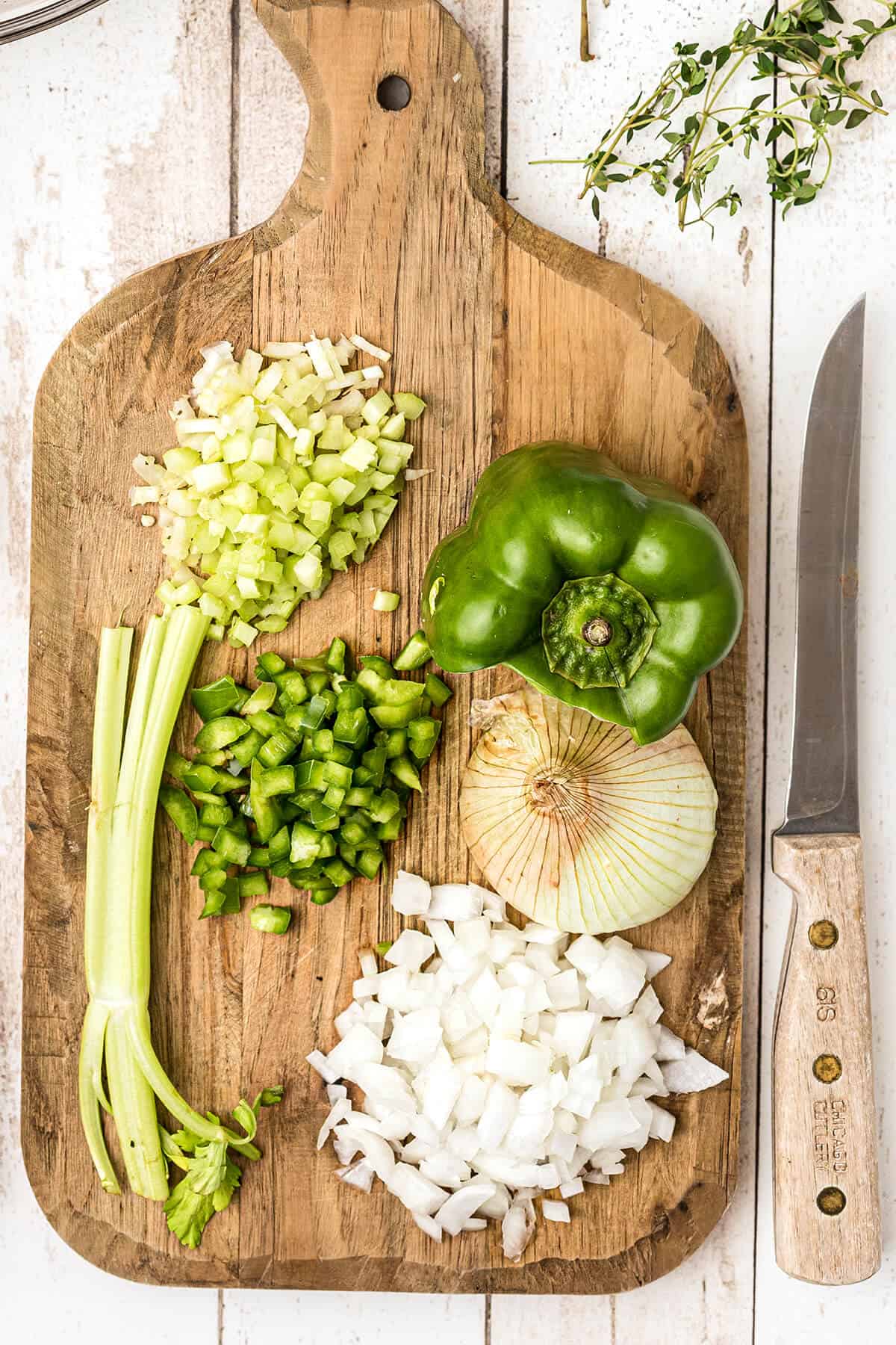 Celery, onion, and bell pepper on a cutting board.