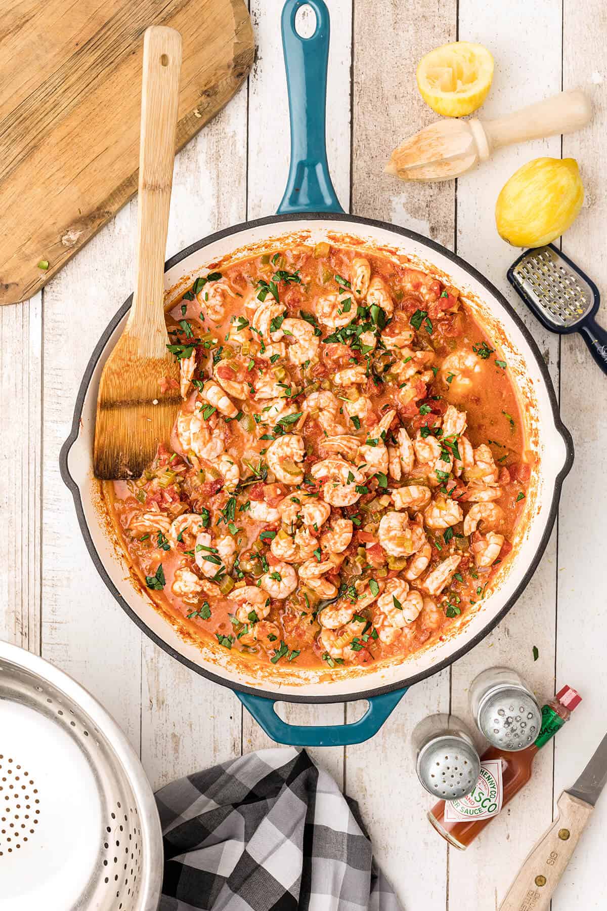 Chopped parsley and lemon juice added to shrimp creole in a skillet.