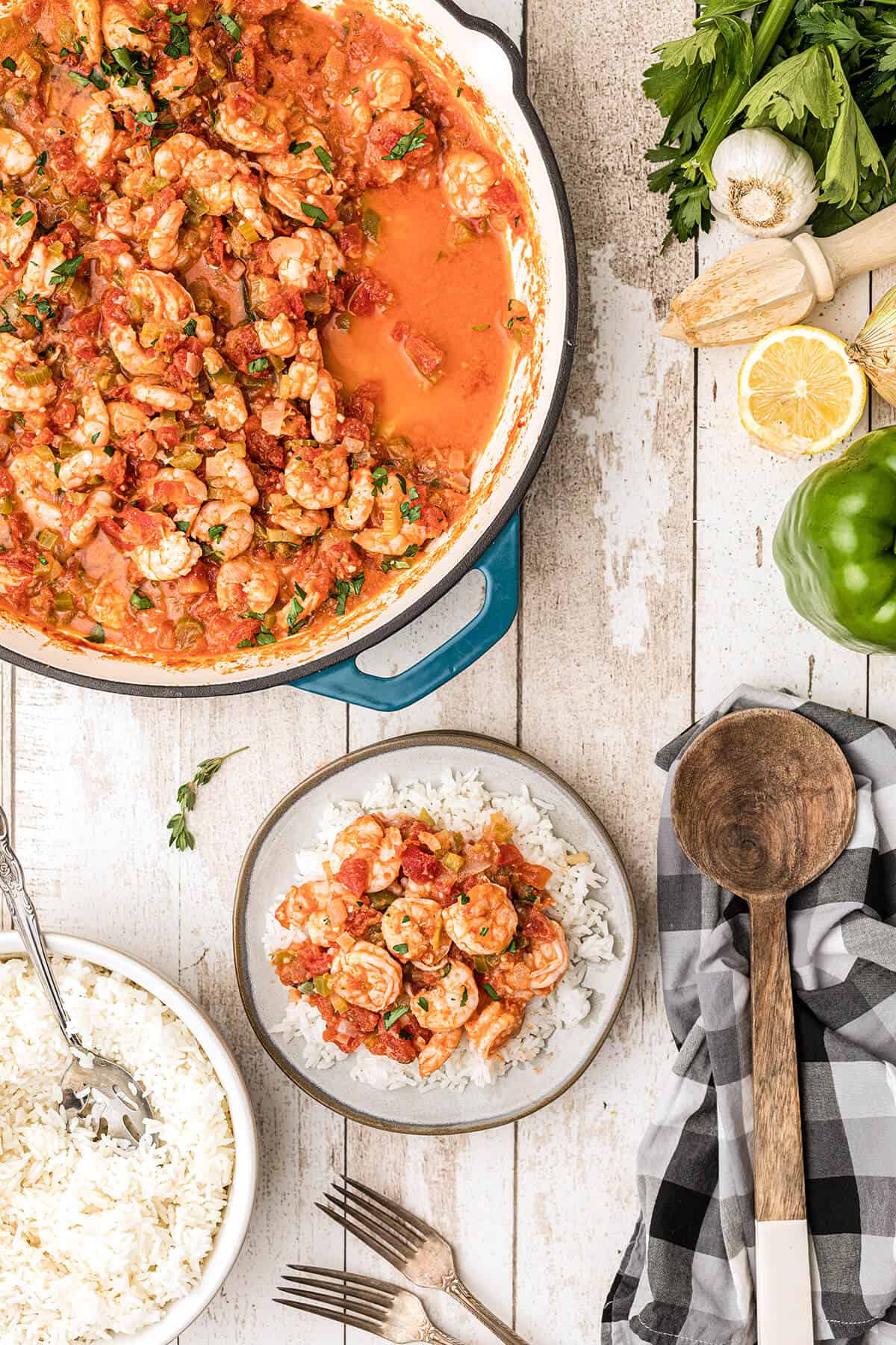 A serving of shrimp creole over white rice on a plate with the pan in the background.