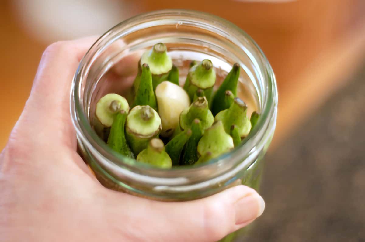 A complete jar packed with okra, garlic, and spices.