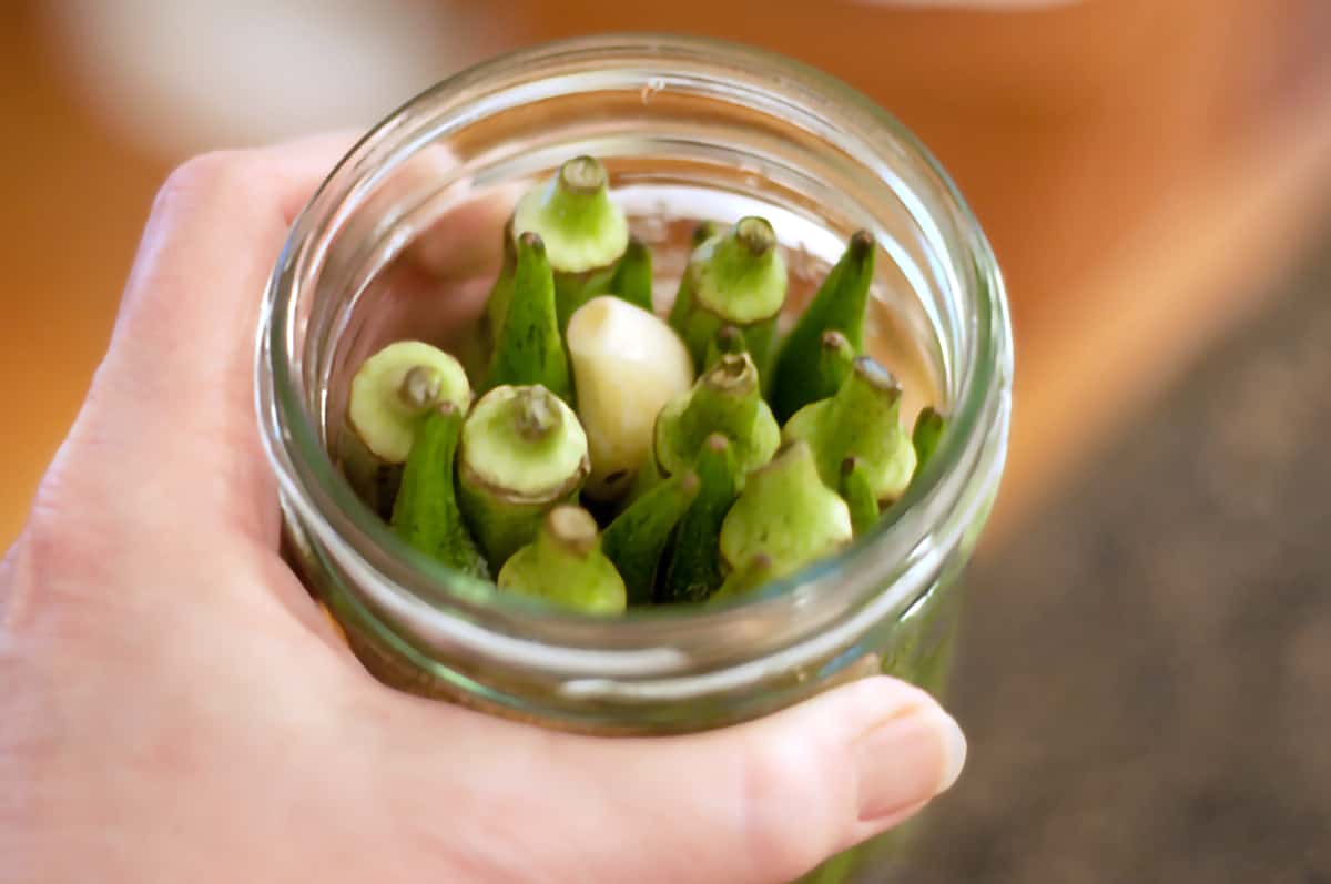 Packing jars of pickled okra A complete jar packed with okra, garlic, and spices.