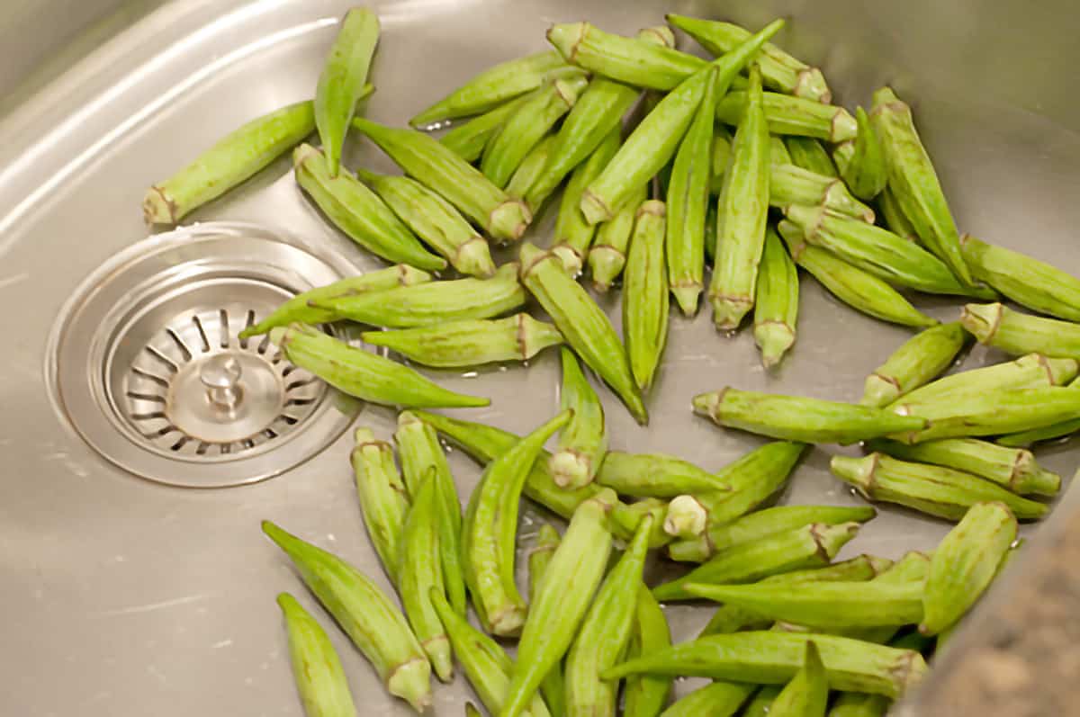 Okra being washed in the kitchen sink.